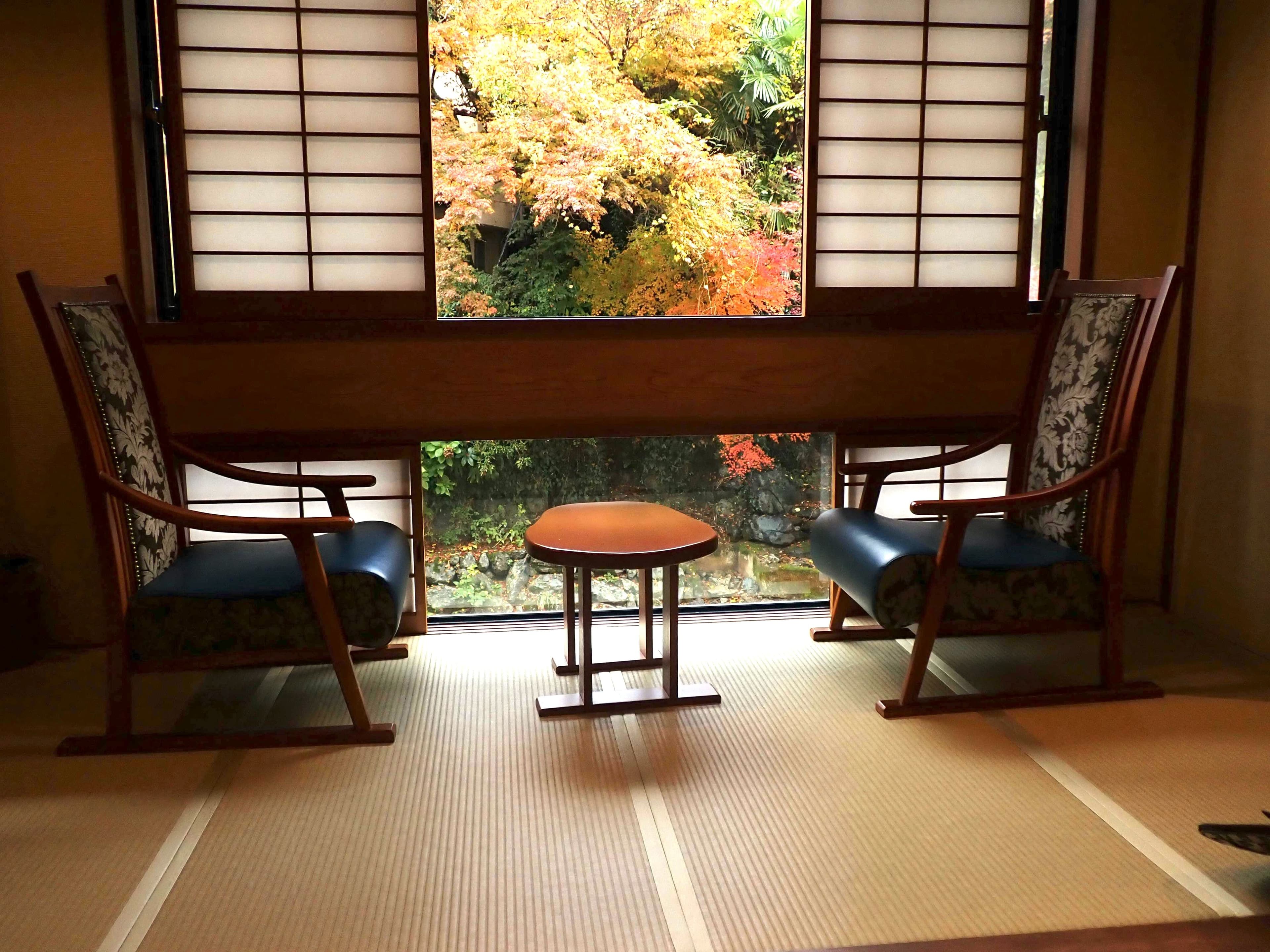 Chambre d'un ryokan avec tatami et chaise devant la fenêtre et momiji.